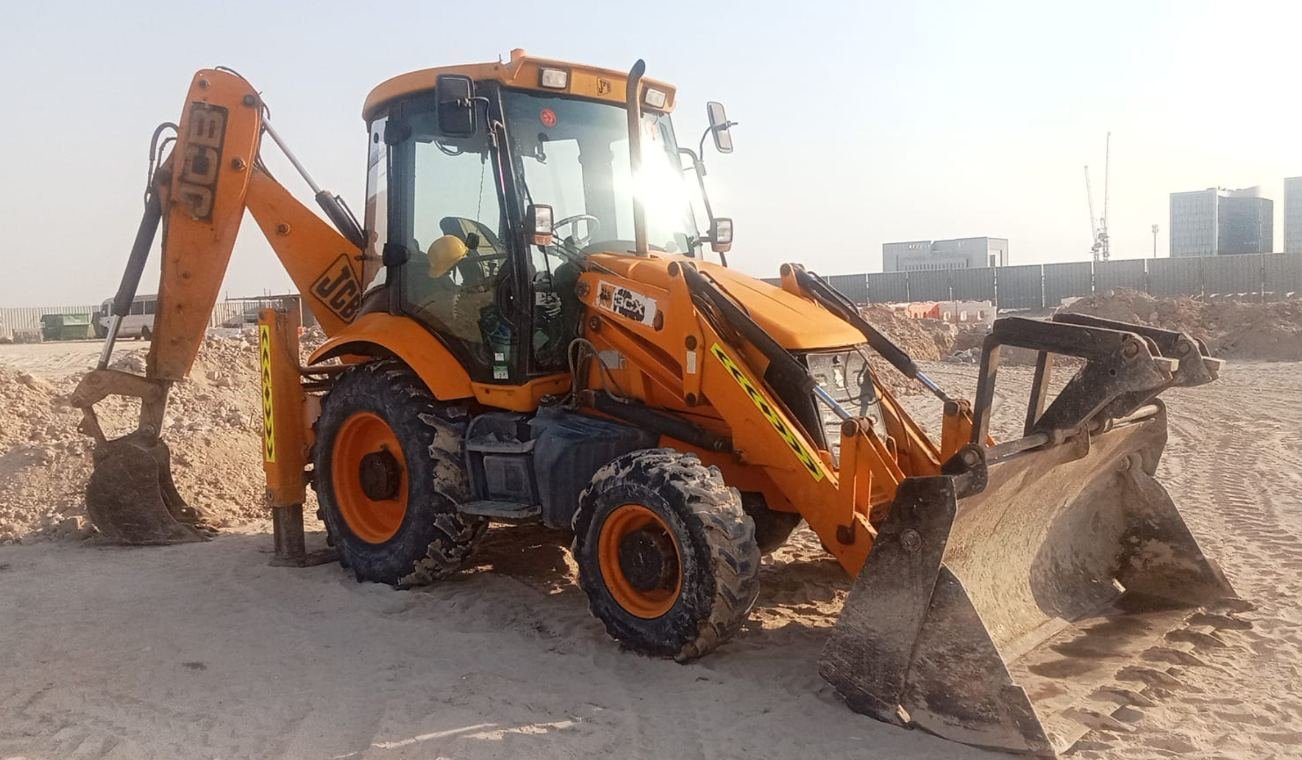 JCB 3CX backhoe loader with stabilisers deployed digging on an Abu Dhabi construction site